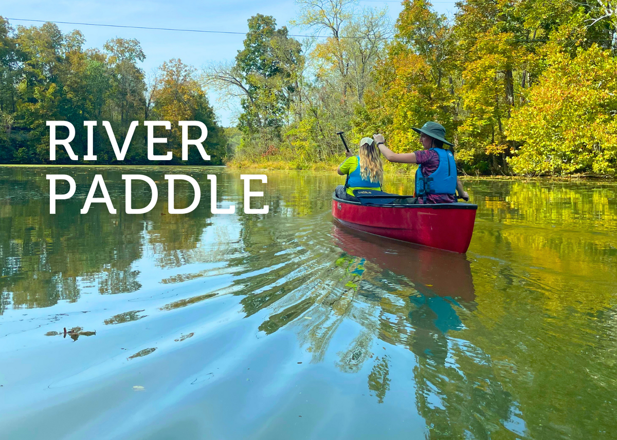 Two people on a red canoe paddle on calm water with "River Paddle" in white lettering